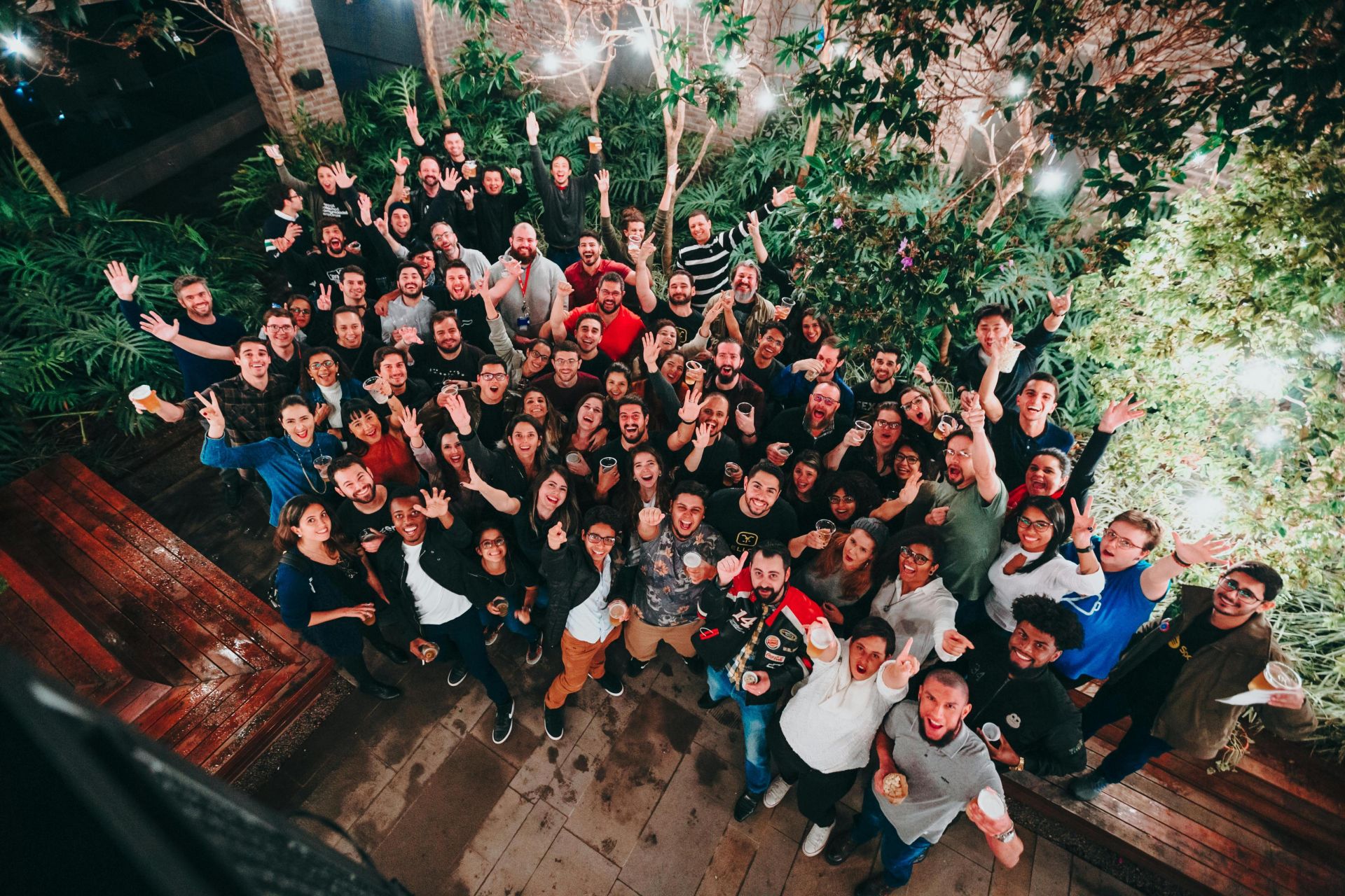 A large group of joyful people posing under string lights in a garden setting. Perfect for joyful and community themes.
