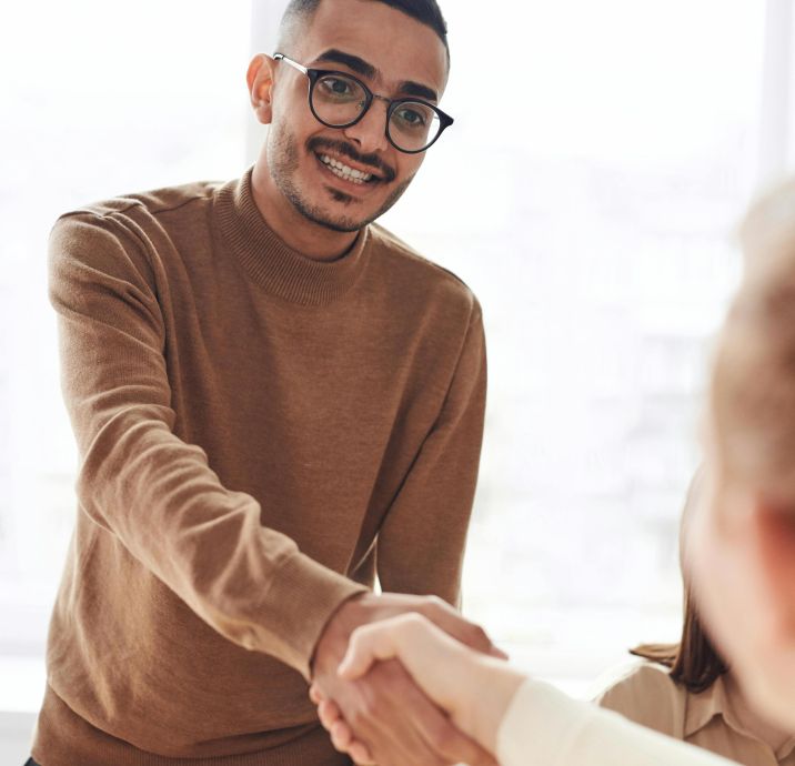 Smiling professionals engage in a welcoming handshake at a business meeting indoors.